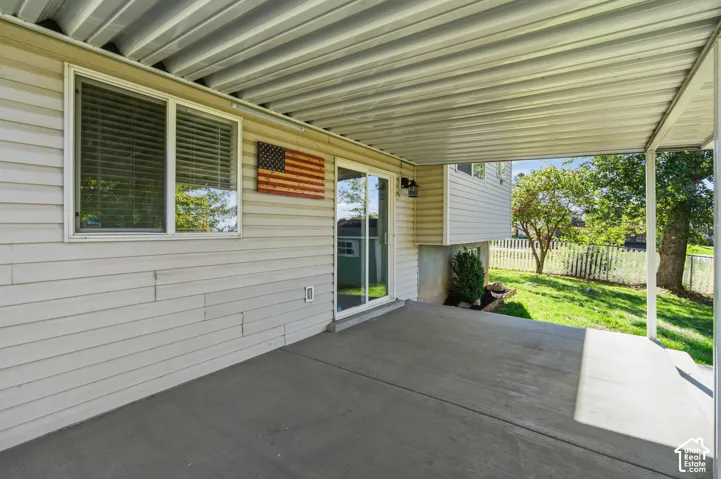 Covered patio with a concrete floor, sliding glass door, metal overhead canopy, and exterior lap siding