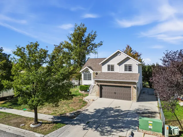 Two-story residence featuring a partial brick exterior, gabled roofline, concrete driveway, and a multi-car attached garage