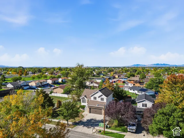 Two-story residence featuring an attached garage, paved driveway, concrete walkway, and landscaped lot with mature trees