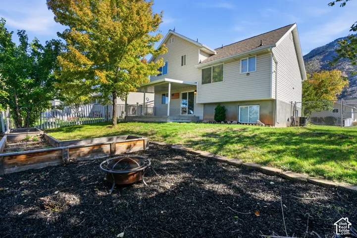 Exterior featuring horizontal siding, a covered rear patio, multi-level tiered garden beds, and mountain scenery