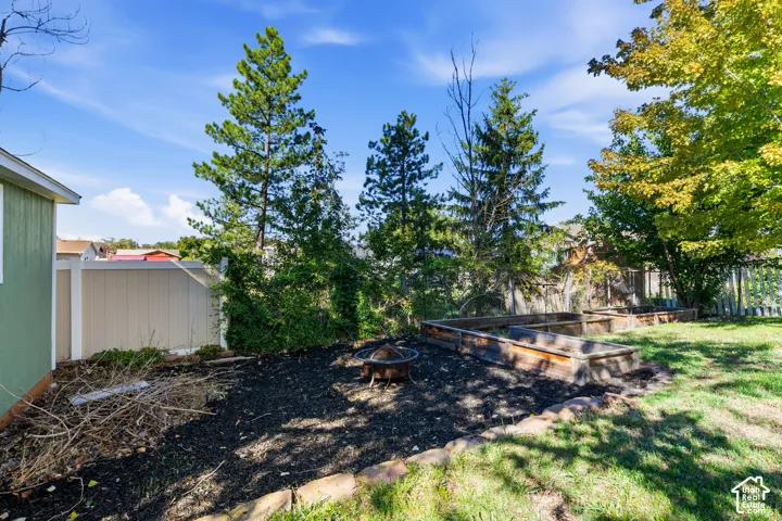 Backyard featuring raised wooden garden beds, stone border edging, and privacy fencing