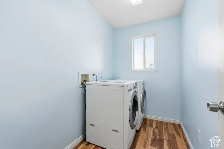 Utility room featuring wood-finish flooring, a single-pane slider window, and recessed utility hookups