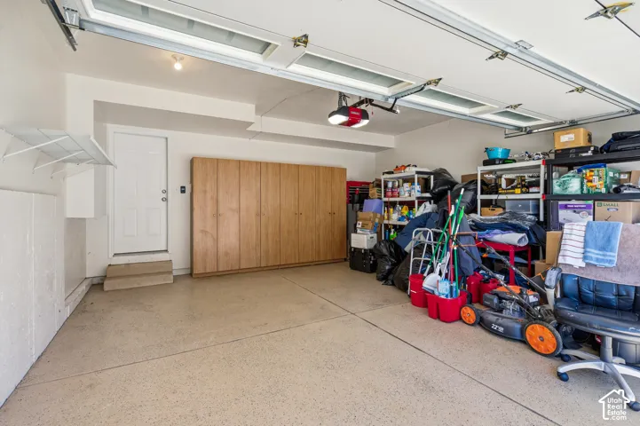 Garage featuring an overhead door with glass inserts, textured epoxy flooring, full-wall wood-finish cabinetry, and a dedicated entry door
