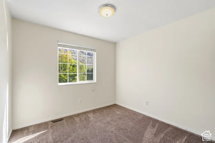Neutral-toned carpeted flooring, window with a grid-pattern sash, and a dome-style flush mount ceiling light fixture