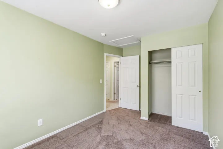 Room featuring wall-to-wall carpeting, six-panel interior doors, and a built-in closet with sliding doors