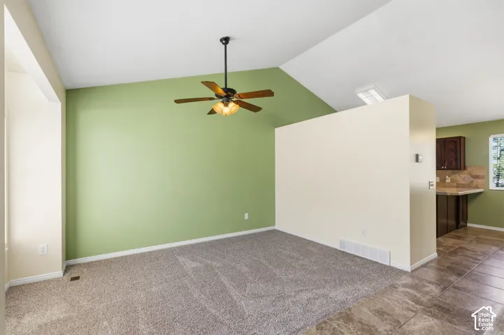 Vaulted ceiling featuring a ceiling fan with integrated lighting and neutral wall tones