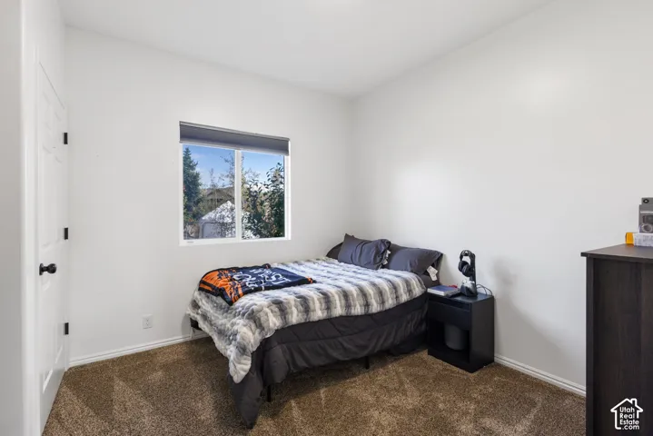Neutral-toned interior space featuring neutral wall paint, wall-to-wall carpeting, and a single-pane window with a roller shade