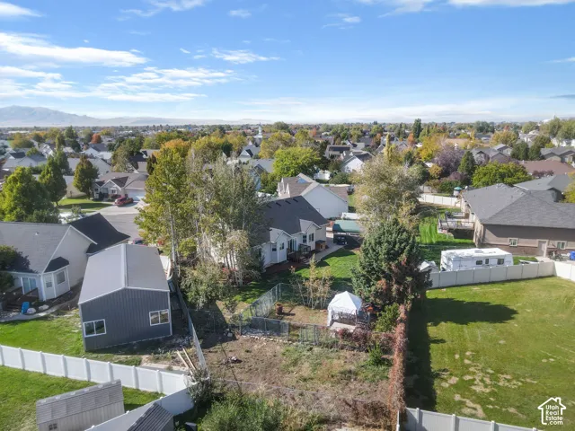 Aerial perspective featuring a detached metal-sided storage structure, fenced yard, and mountain backdrop