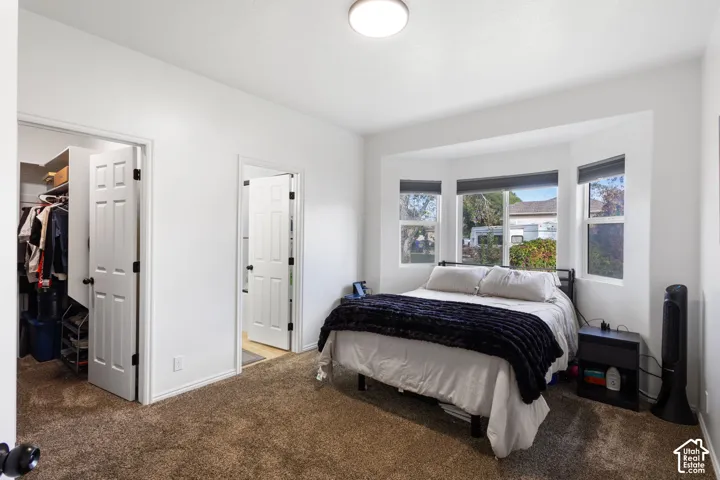 Room featuring a bay window, wall-to-wall carpeting, and two interior doors providing access to a walk-in closet and additional space