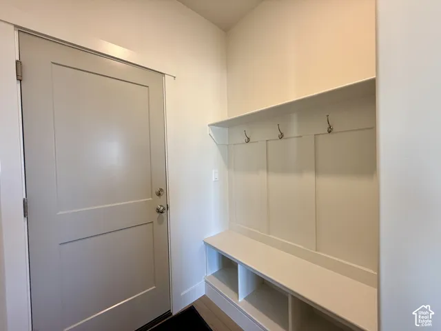 Built-in mudroom bench featuring partitioned storage cubbies, integrated wall paneling, an upper shelf, and three metal coat hooks