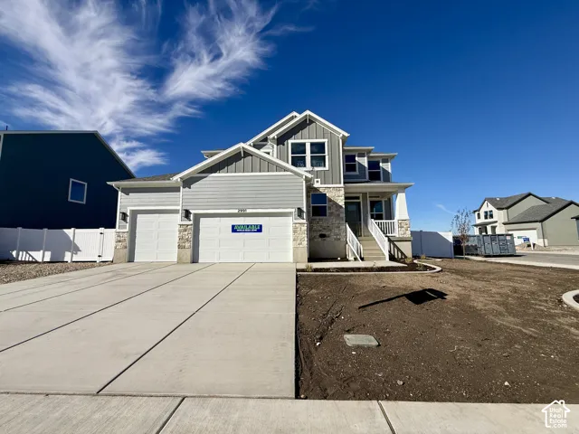 Two-story exterior featuring horizontal lap siding, vertical board-and-batten accents, stone veneer detailing, a covered front porch with white railing, and an attached three-car garage