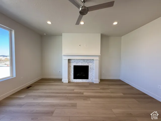 Fireplace with white mantel and herringbone tile surround, wood-finish flooring, recessed lighting, and a contemporary ceiling fan