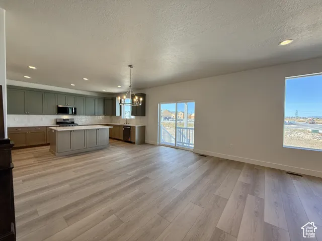Open-concept interior featuring wood-finish flooring, recessed lighting, cabinetry with stone countertops, a center island, and a sliding glass door
