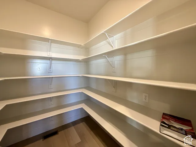 Custom built-in storage featuring tiered shelving, wood-finish flooring, and wall-mounted electrical outlets