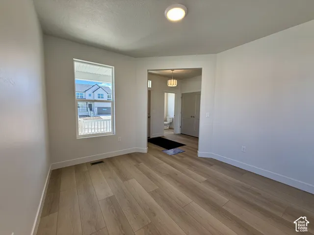 Room featuring wood-finish flooring, neutral walls, a single-pane window, flush-mount ceiling lighting, and double-door closet cabinetry
