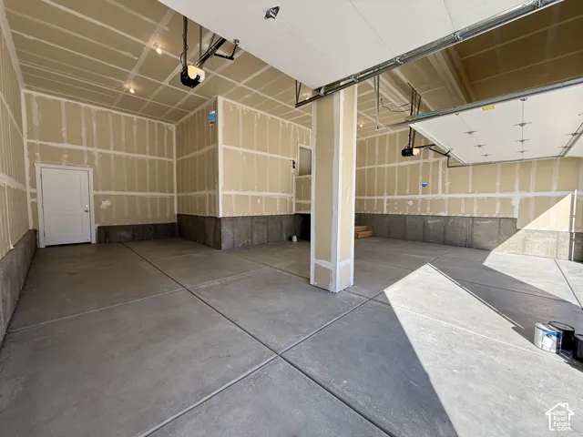 Multi-car garage featuring a concrete floor, two overhead door openers, and a dedicated entry door