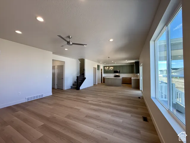 Open-concept interior featuring wood-finish flooring, recessed lighting, a modern ceiling fan, and large windows