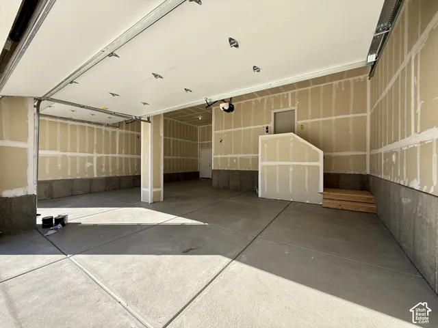 Spacious multi-car garage featuring a concrete floor, automated overhead door, and dual interior access doors