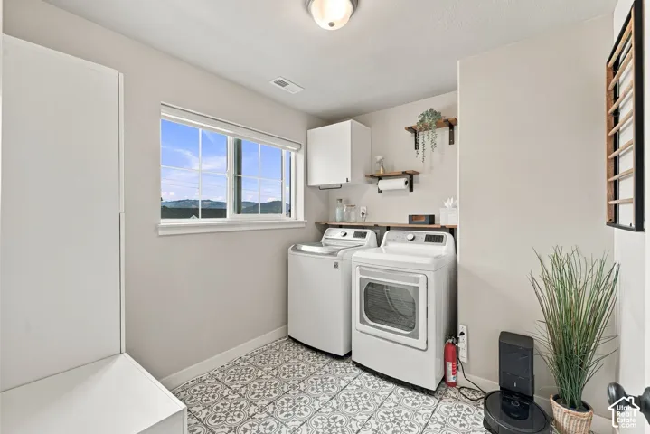 Laundry space featuring patterned tile flooring, white cabinetry, open wooden shelving, and a window with mountain scenery