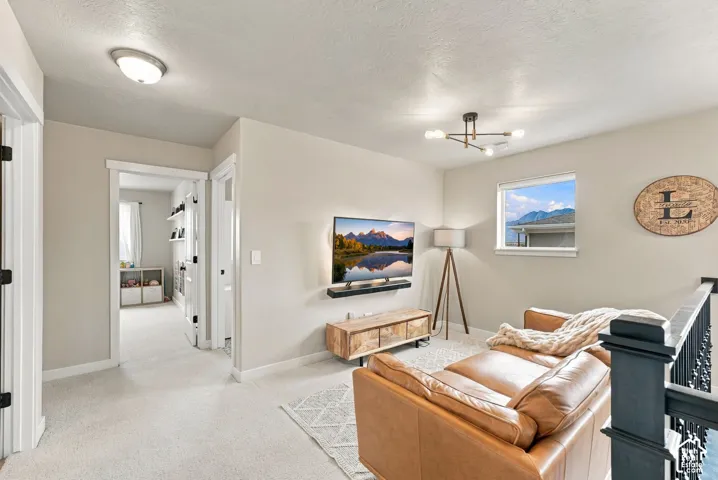 Neutral-toned interior featuring carpeting, a contemporary multi-arm light fixture, a window with mountain scenery, and a dark-finished balustrade
