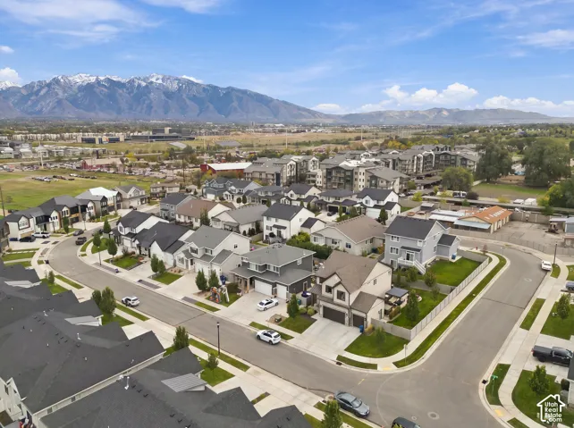 Aerial perspective of residential neighborhood featuring multi-level dwellings with concrete driveways, attached garages, and a backdrop of mountain peaks
