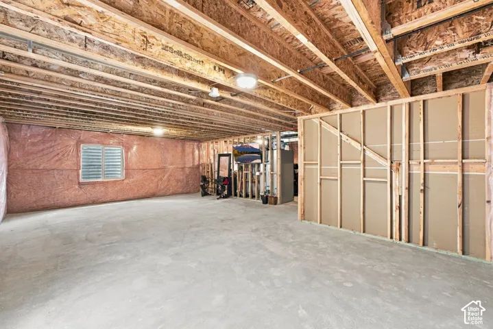 Unfinished lower level featuring exposed wood joist ceilings, concrete flooring, insulated wall segments, and a single window
