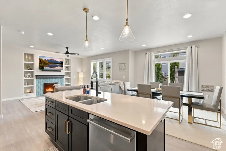 Kitchen featuring a center island with quartz countertops, dual-basin sink, and dark cabinetry