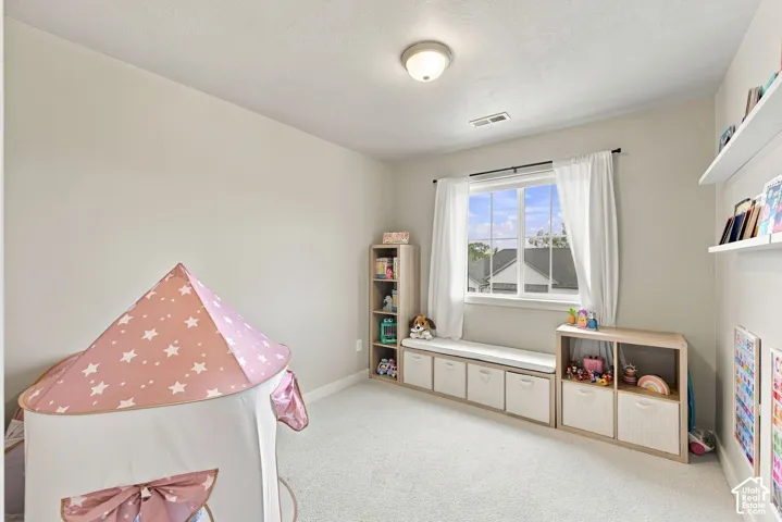 Neutral-toned interior featuring wall-to-wall carpeting, a large sliding window with grid detail, a built-in window bench with integrated lower cabinetry, and wall-mounted floating shelving