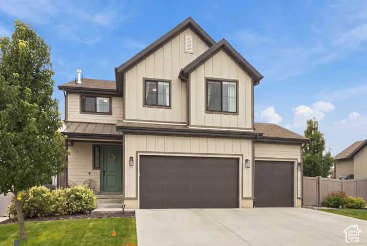 Two-story exterior featuring board and batten siding, mixed horizontal lap siding, metal roof accents, and a three-car garage
