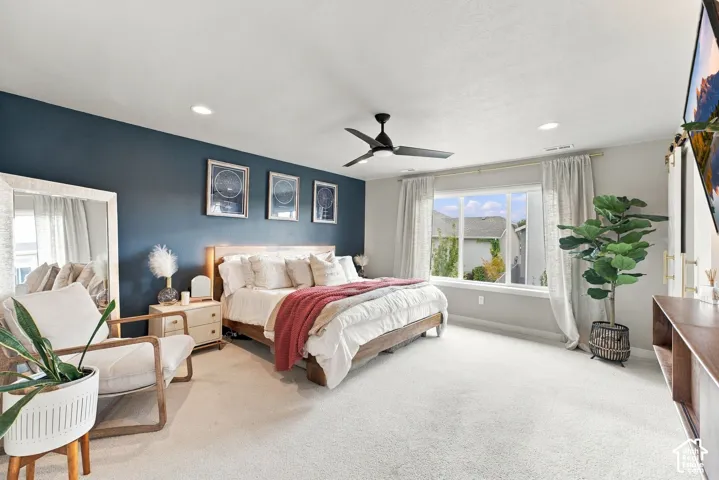 Spacious room featuring a deep-toned accent wall, large picture window, ceiling fan with integrated lighting, neutral carpeting, and recessed ceiling lighting