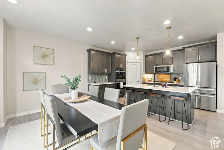 Kitchen featuring dark-finish cabinetry, stone-surface countertops, stainless steel appliances including a built-in oven and microwave, recessed lighting, and a center island with pendant fixtures