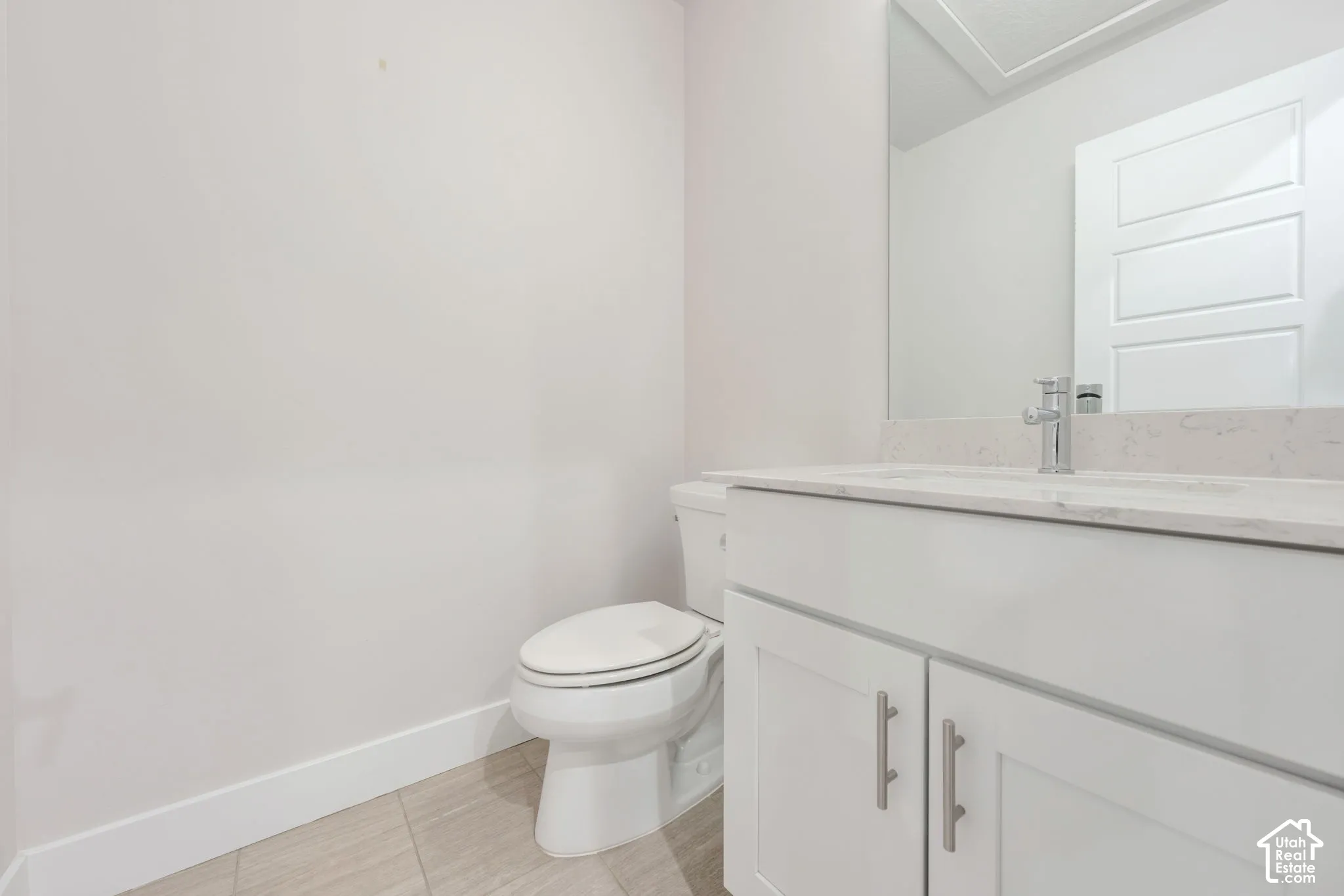 Bathroom featuring a white shaker-style vanity with a neutral stone countertop, undermount sink, chrome faucet, and tile flooring