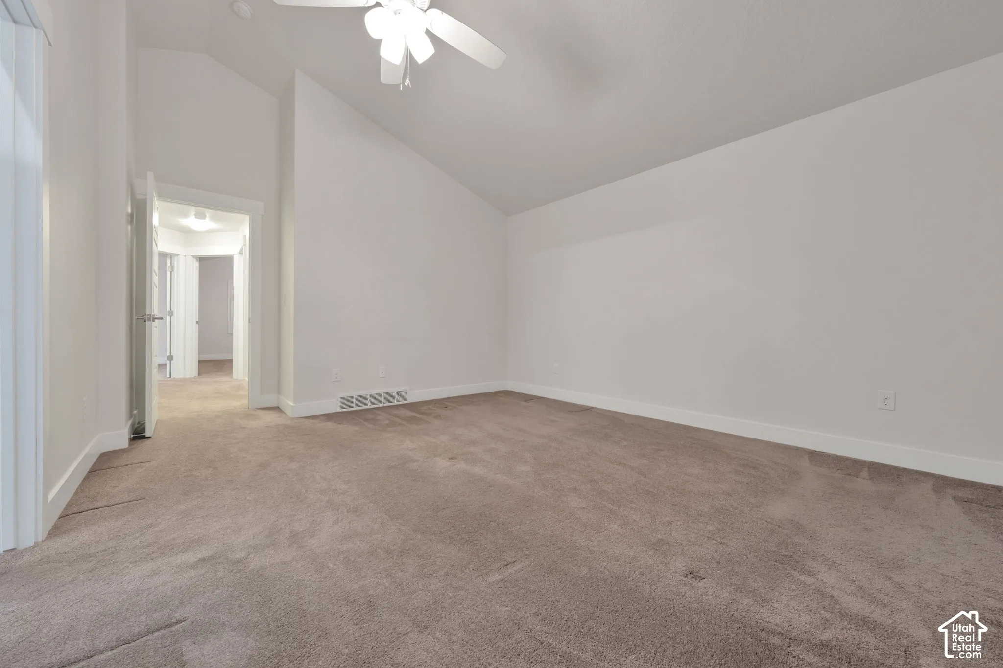 Vaulted ceiling featuring a ceiling fan with integrated lighting and neutral wall-to-wall carpeting
