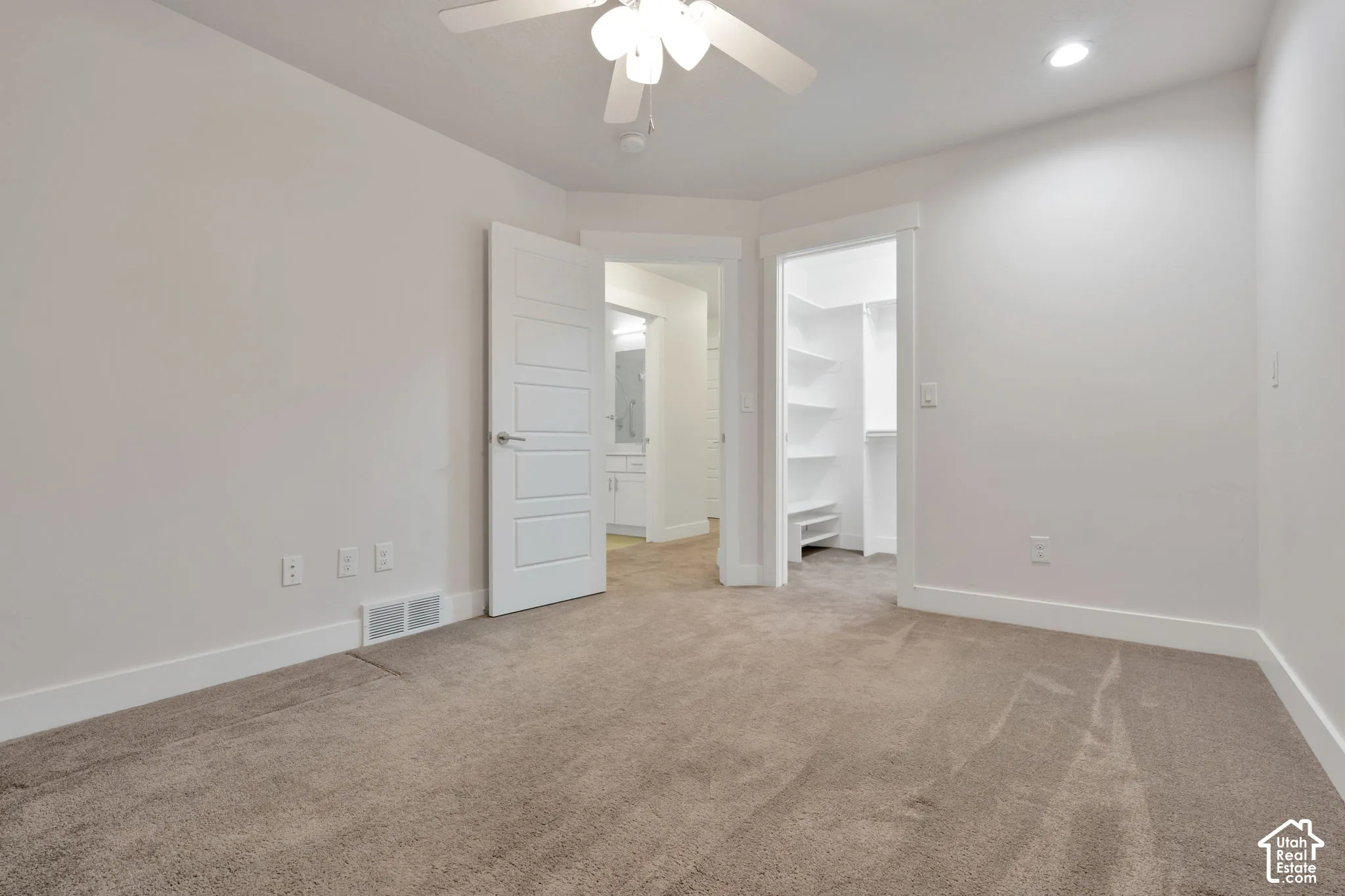 Neutral interior featuring wall-to-wall carpeting, a multi-panel door, built-in closet shelving, and a ceiling-mounted light fixture