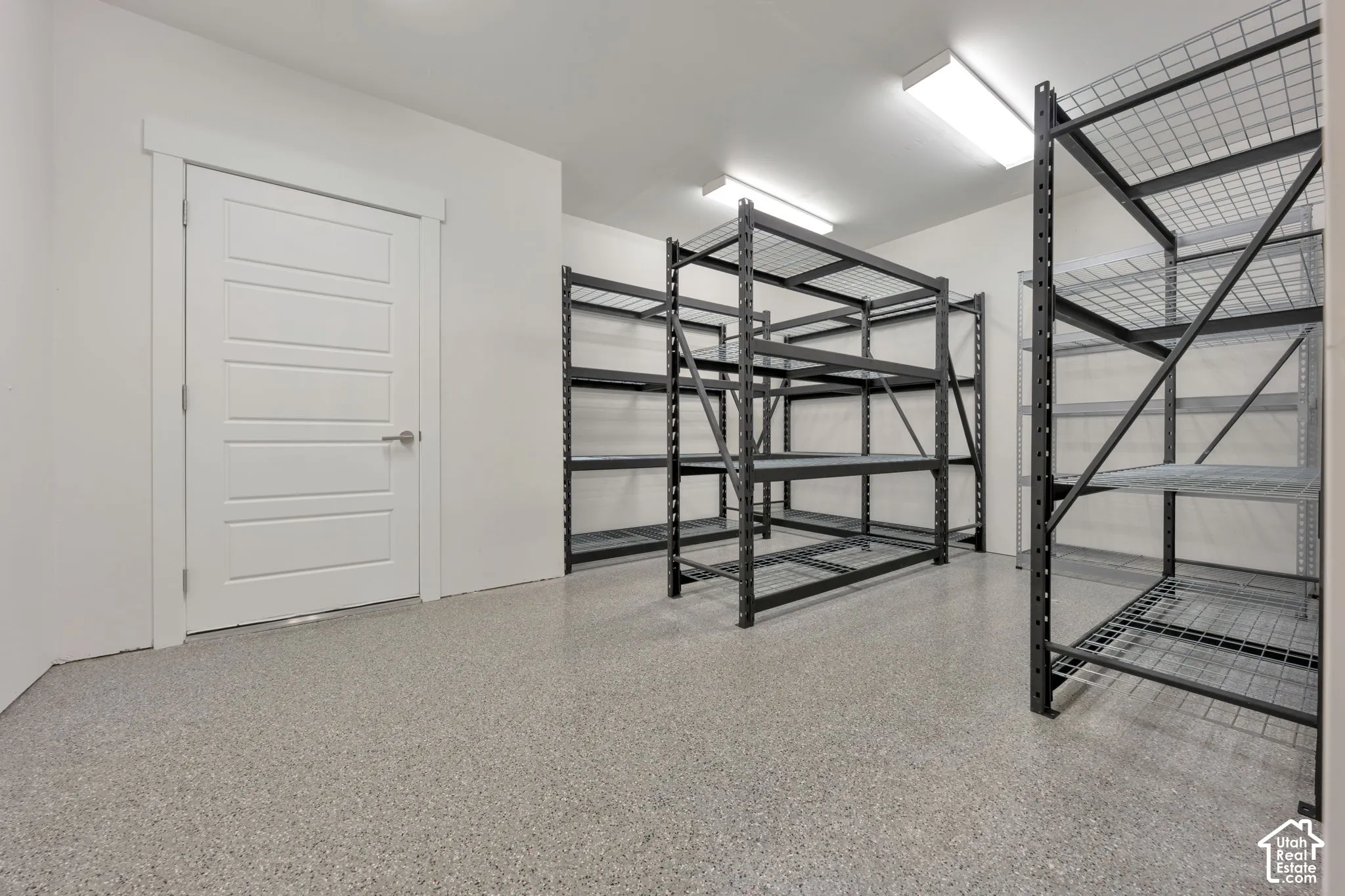 Finished storage space featuring durable epoxy flooring, bright LED overhead lighting, and white interior trim with a solid-core door