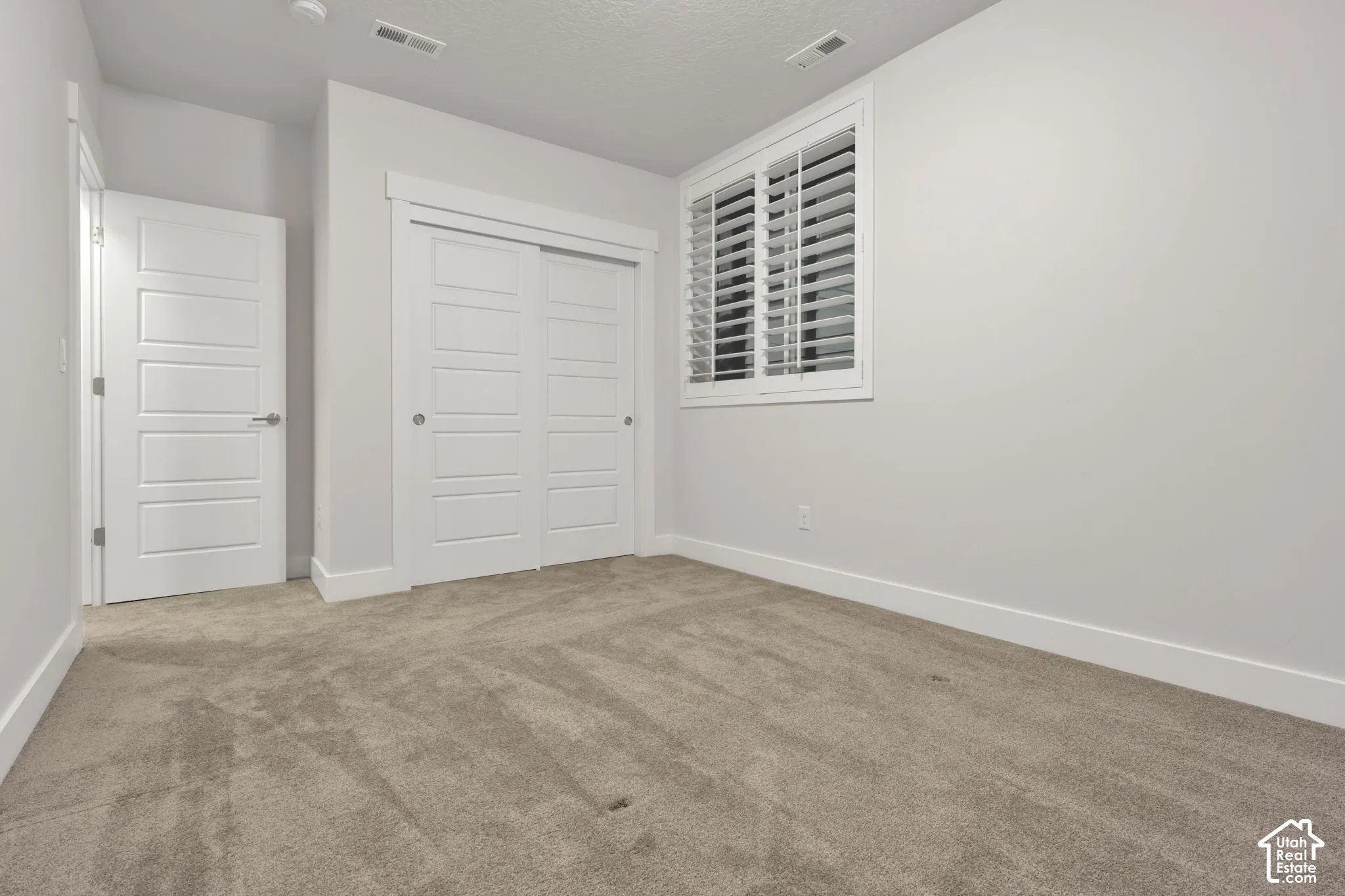 Neutral-toned carpeting, white four-panel interior doors, and sliding closet doors with matching trim