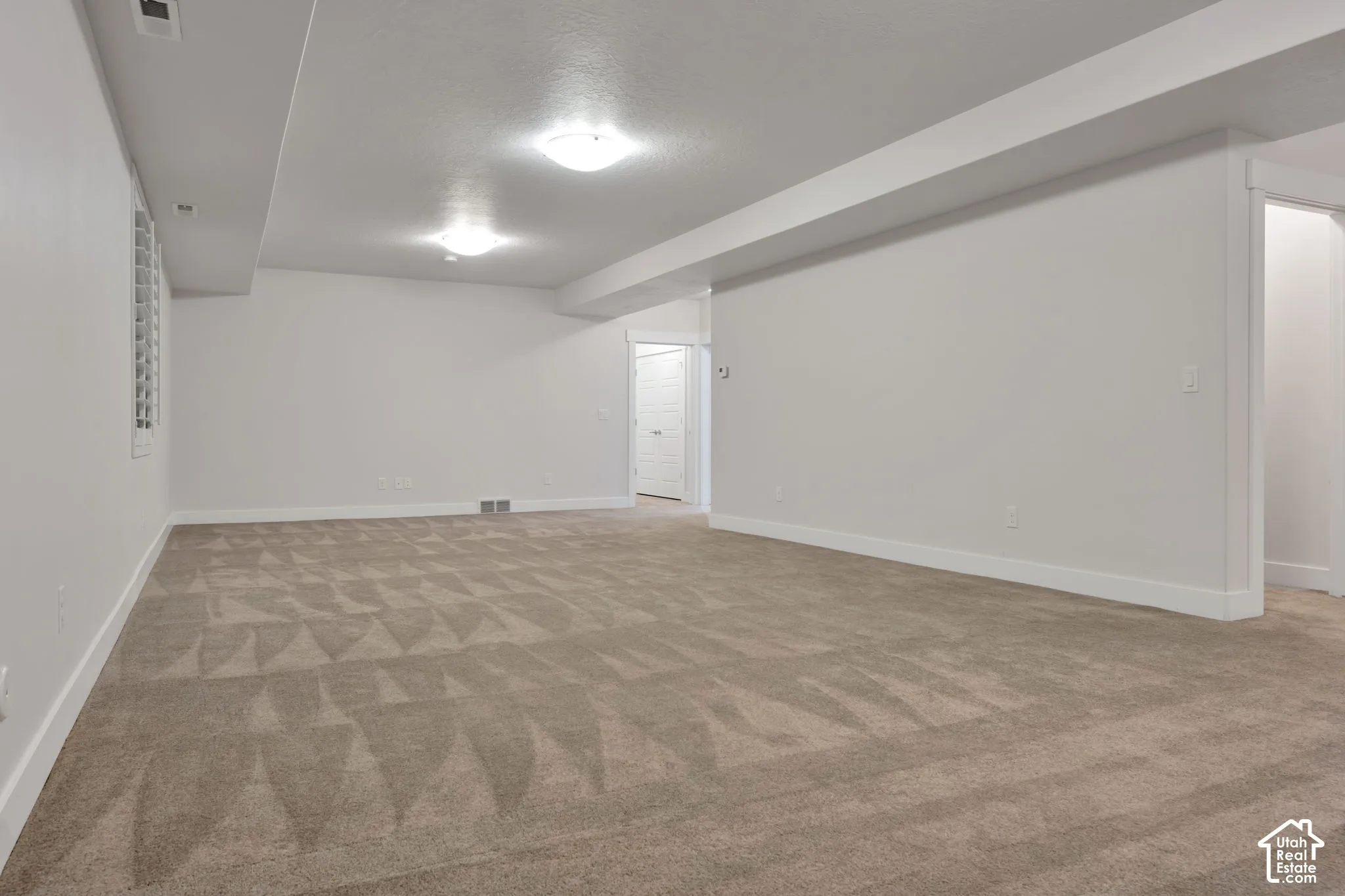 Neutral interior room with wall-to-wall carpeting, recessed ceiling lighting, and crisp white walls
