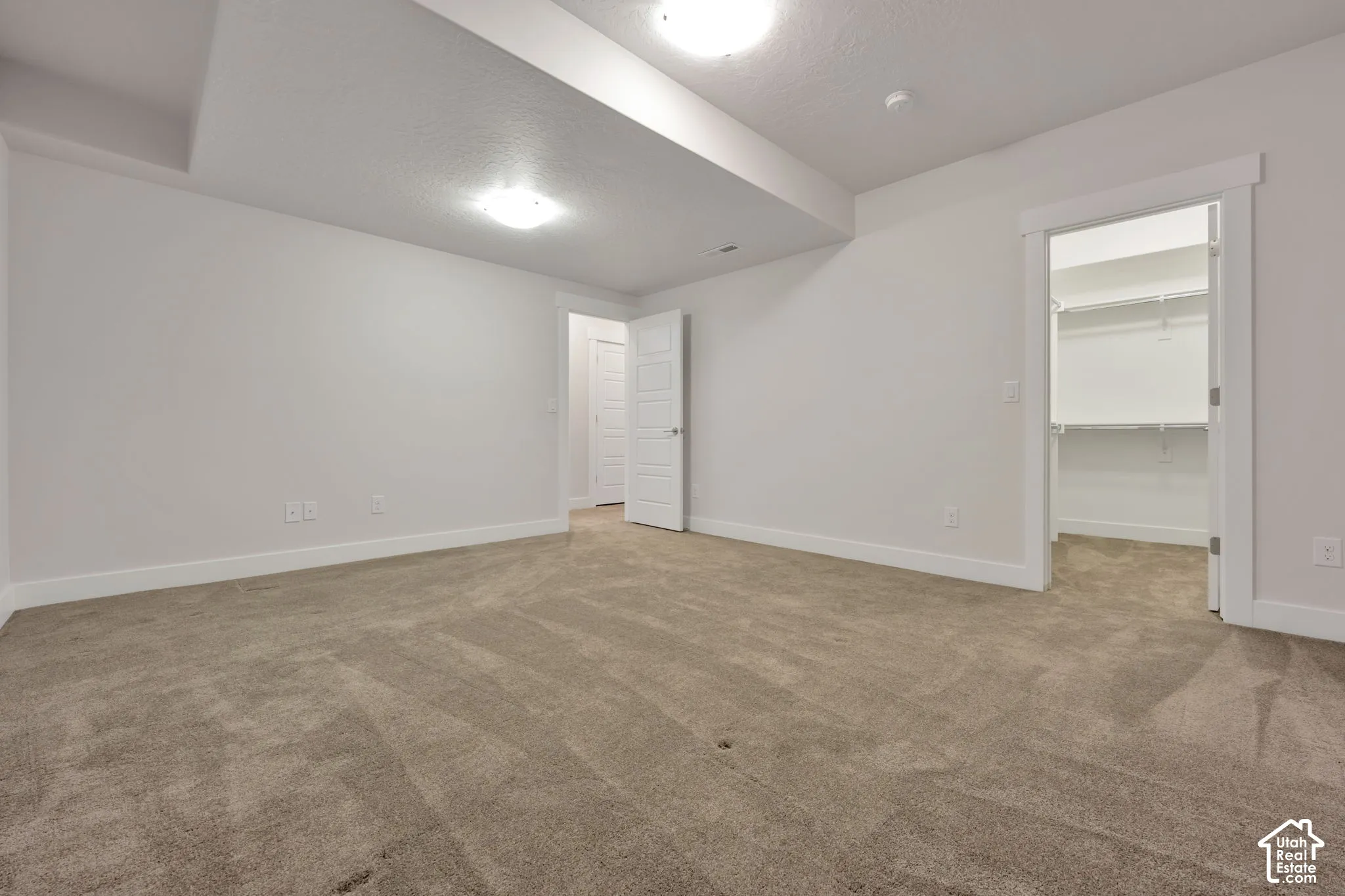 Neutral-toned wall-to-wall carpeting, recessed ceiling lighting, and a walk-in closet featuring built-in shelving