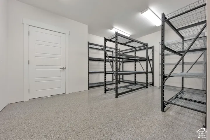 Finished storage space featuring durable epoxy flooring, bright LED overhead lighting, and white interior trim with a solid-core door