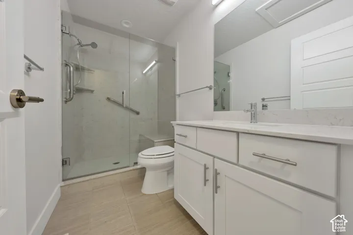 White shaker-style vanity with a stone countertop, glass-enclosed shower with tiled surround, built-in shower bench, and polished metal hardware