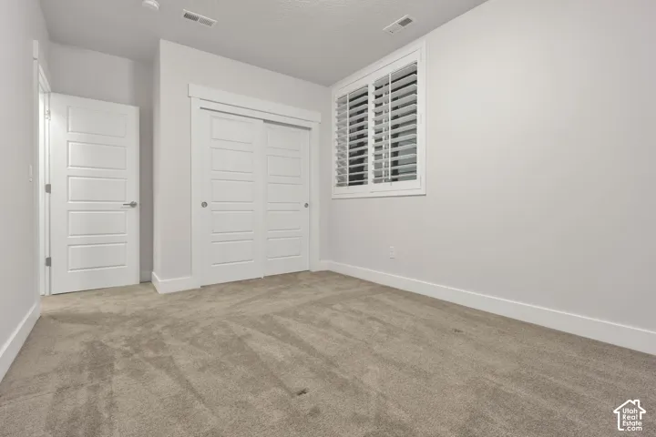 Neutral-toned carpeting, white four-panel interior doors, and sliding closet doors with matching trim