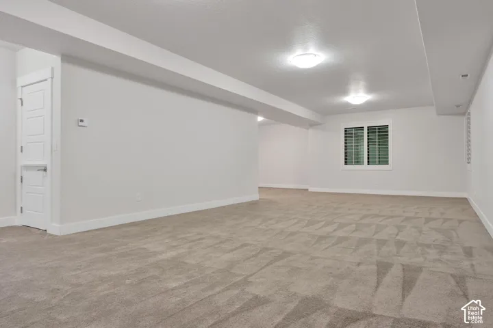 Neutral-toned carpeting, neutral wall paint, flush-mount ceiling lighting, and a window with plantation shutters