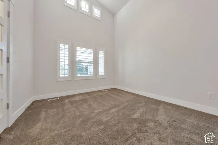 Vaulted ceilings featuring high-reach windows, wall-to-wall carpeting, and adjustable plantation shutters