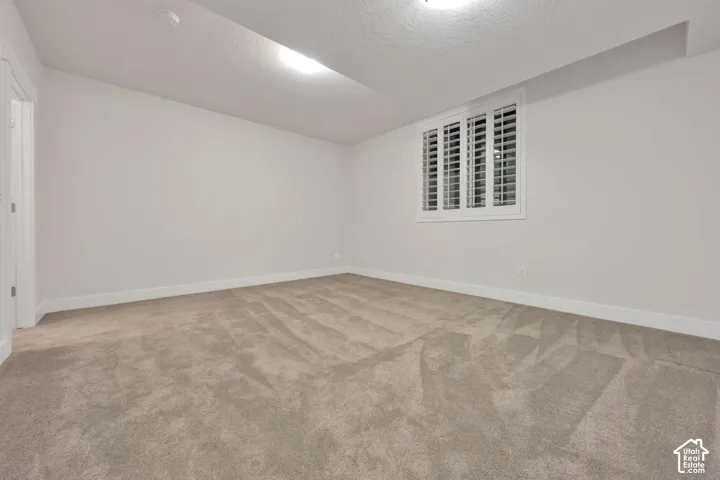 Room featuring neutral wall-to-wall carpeting, white walls, and a window fitted with white plantation shutters