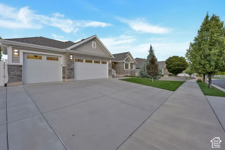 Exterior facade featuring a combination of stone masonry and siding, a three-car garage, and a concrete driveway