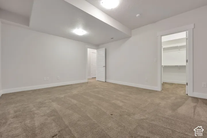 Neutral-toned wall-to-wall carpeting, recessed ceiling lighting, and a walk-in closet featuring built-in shelving