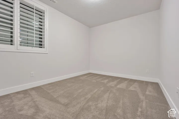 Neutral-toned carpeted flooring, walls finished in a crisp neutral paint, and window shutters