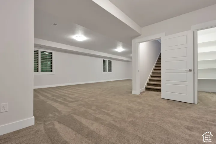 Open-concept room with neutral wall-to-wall carpeting, recessed flush-mount ceiling lighting, white interior doors, and built-in shelving