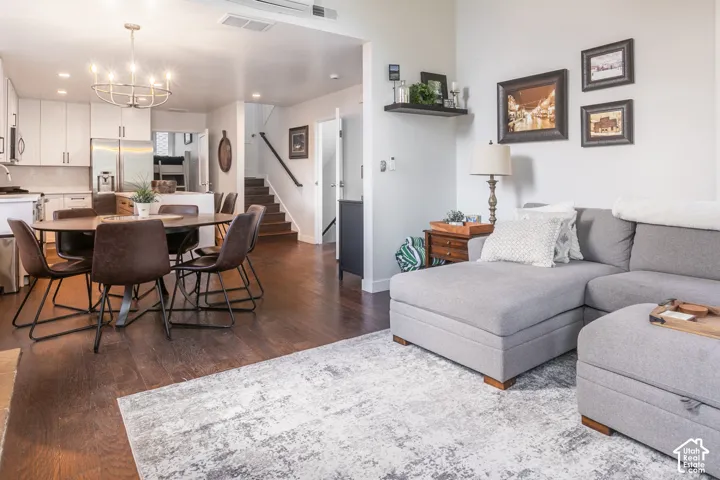 Recessed lighting, wood-finish flooring, white cabinetry, stainless steel appliances, and a modern chandelier