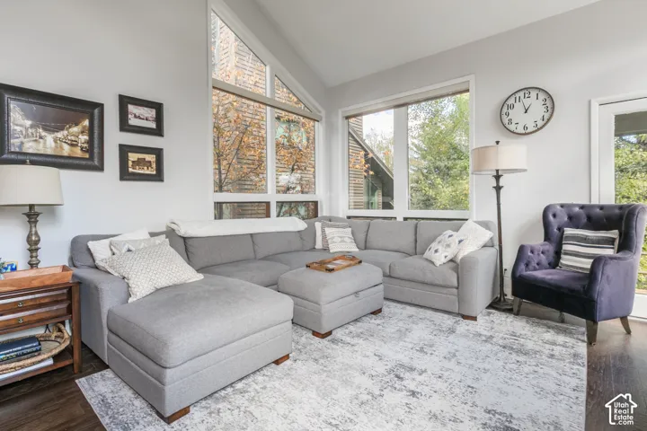 Vaulted ceiling with a large triangular window, additional windows, and wood-finish flooring